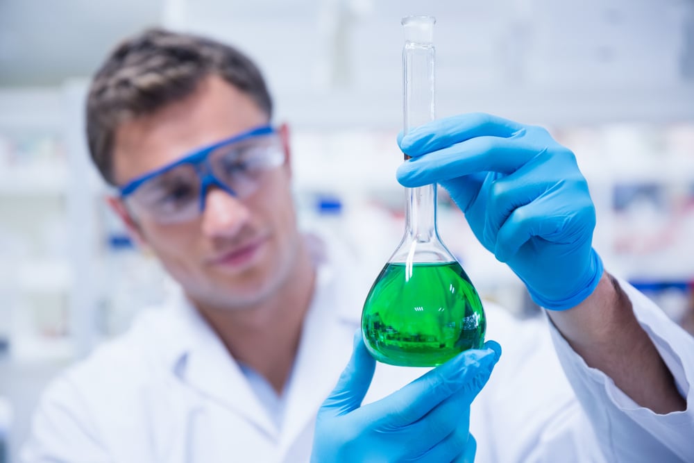 Chemist holding up beaker of green chemical in the laboratory-2