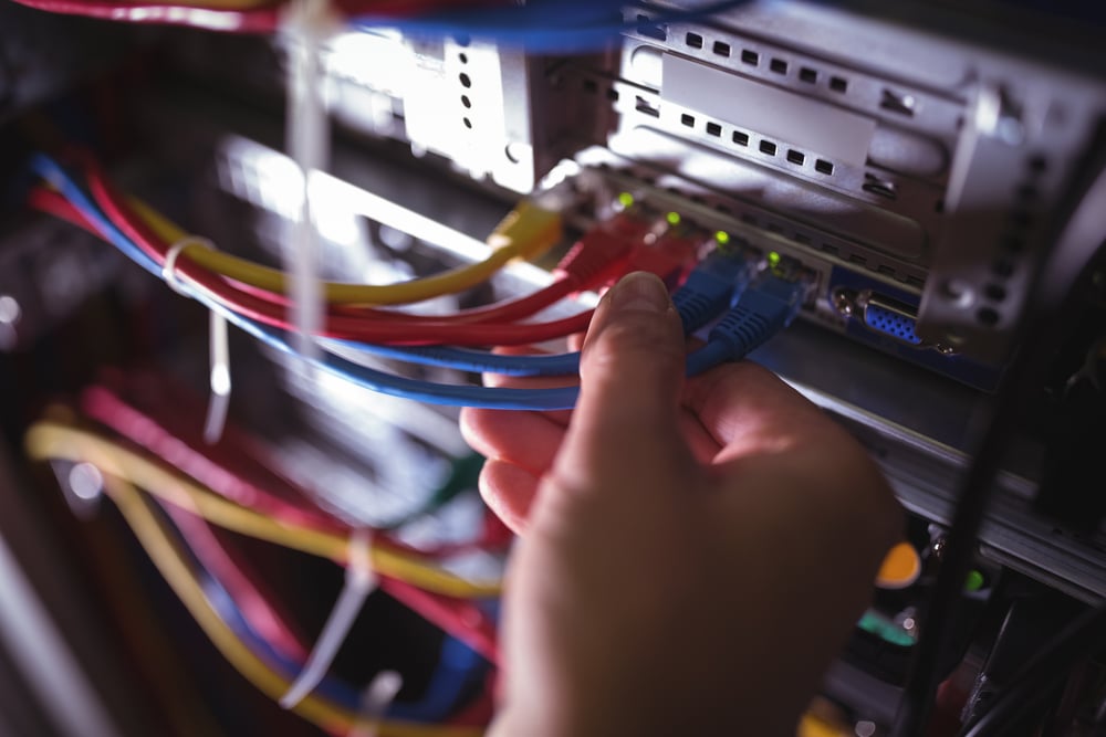 Close-Up of technician plugging patch cable in a rack mounted server in server room