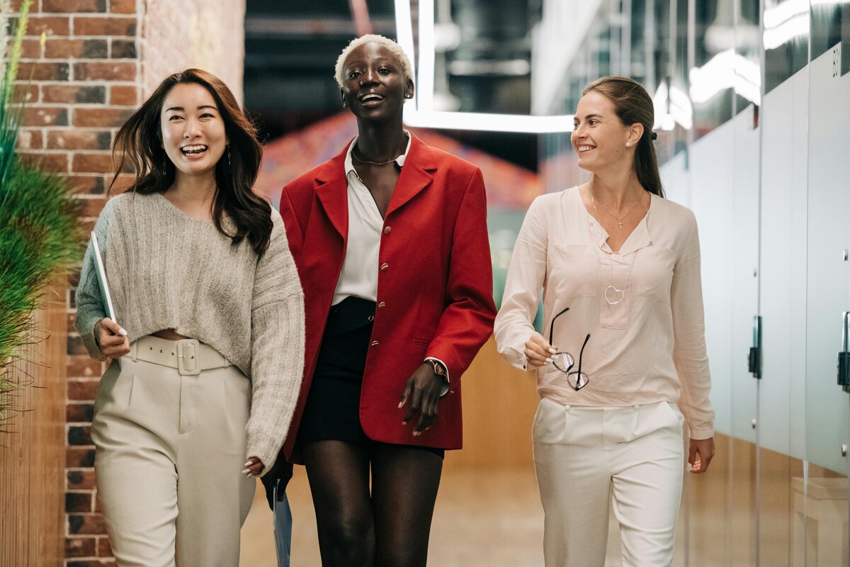 Three smiling women walking in an office