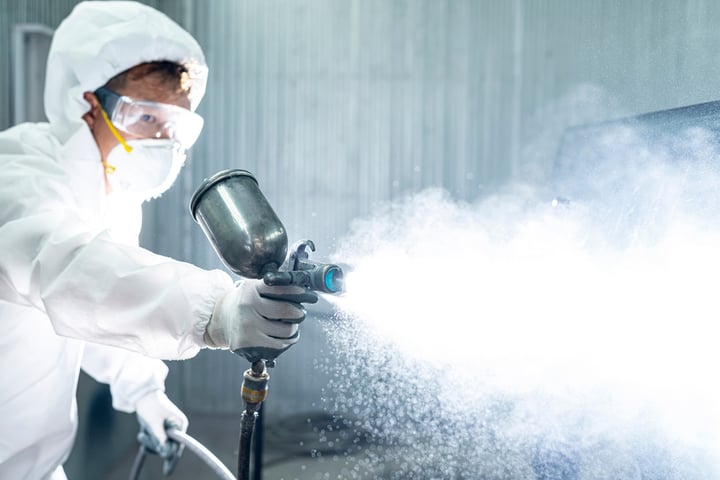 worker spraying chemical solution while wearing protective equipment