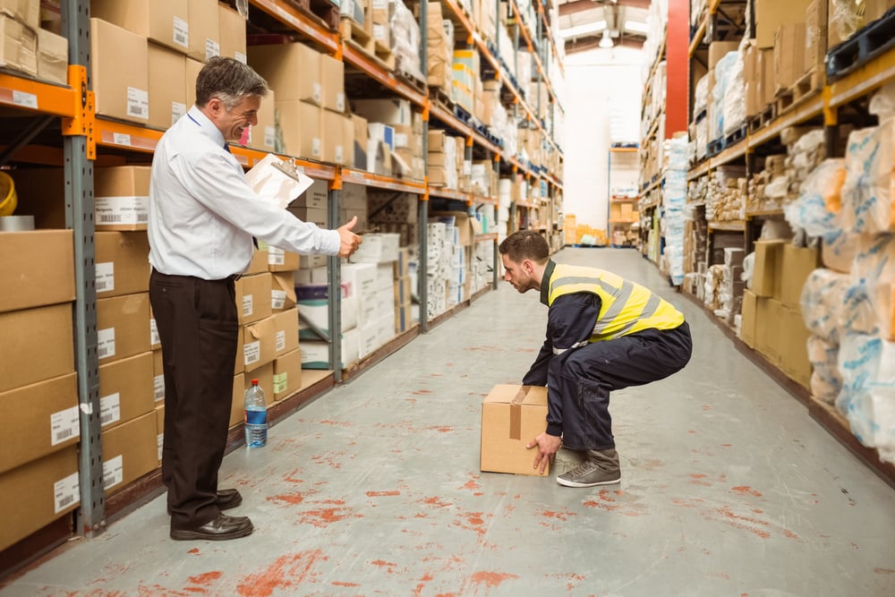 Manager watching worker carrying boxes in a large warehouse-1