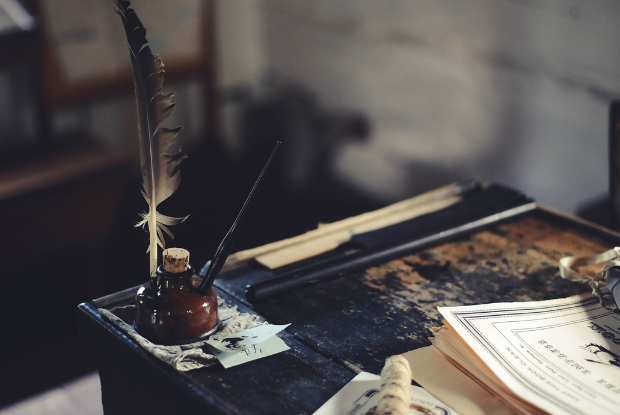 Image of a quill and ink pot on a desk