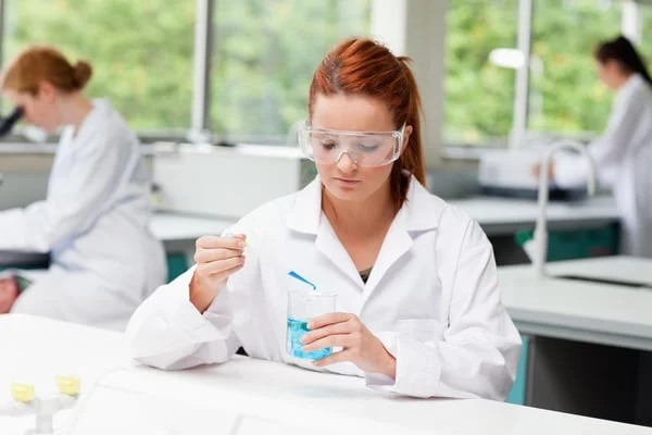 Science20student20dropping20liquid20in20a20beaker20while20her20classmates20are20working20in20a20laboratory-8