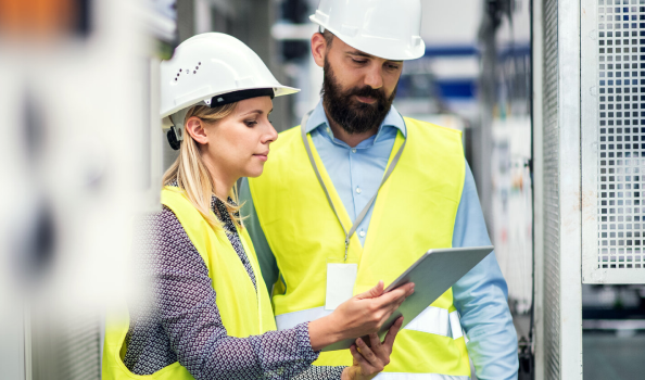 two workers in safety gear review clipboard