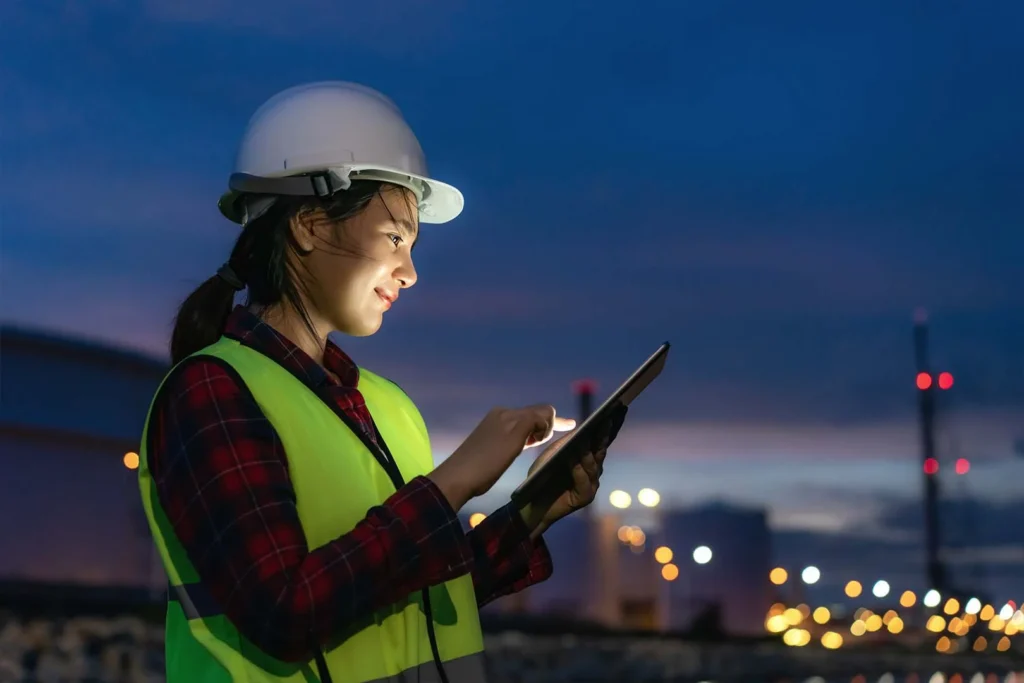 woman wearing hardhat checking tablet