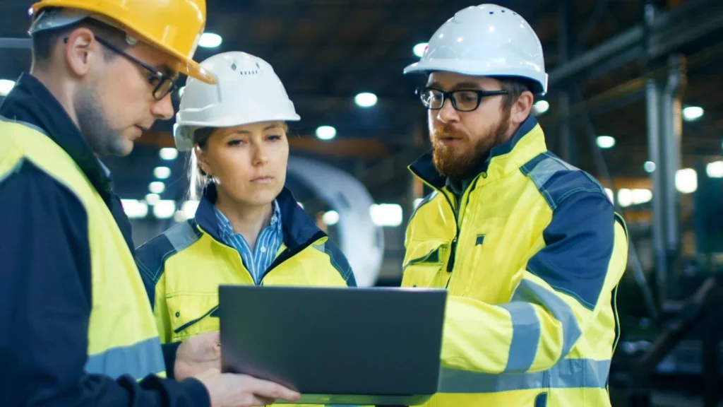 SDS three people with hard hats looking at screen
